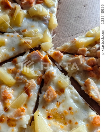 Savory slice of pizza topped with chicken and pineapple on wooden surface Savory slice of pizza topped with chicken and pineapple on wooden surface 133548936