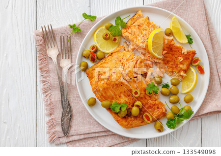 roasted salmon fillet on plate with green olives 133549098