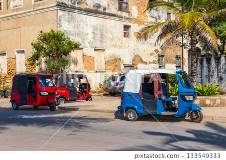 Tuk-tuks, parked by the roadside, in the historic Stone Town of Zanzibar, Tanzania 133549333