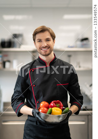 Cook standing and holding dish with pepper cucumber and tomato Cook standing and holding dish with pepper cucumber and tomato 133549574