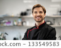 Chef in uniform standing smiling in restaurant kitchen 133549583
