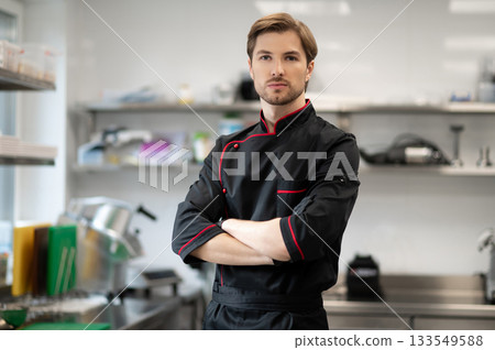 Chef standing with crossed arms in kitchen Chef standing with crossed arms in kitchen 133549588