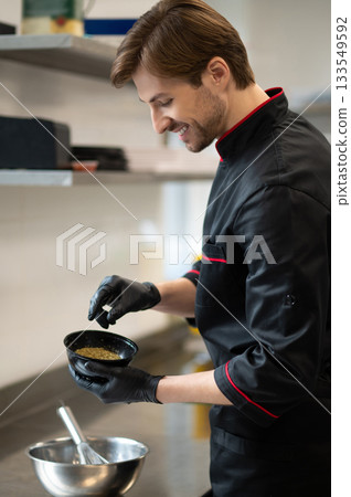 Chef adding spices into metal mixing bowl in kitchen Chef adding spices into metal mixing bowl in kitchen 133549592