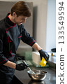 Cook in black chef uniform preparing sauce in kitchen 133549594