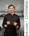 Cook holding two halves of pepper during food preparation 133549600