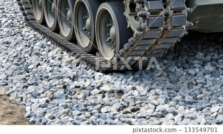 Heavy machinery moves over gravel surface during military training exercise in a rural area under clear skies 133549701