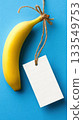 Bright yellow banana with a blank tag on a blue background ready for labeling 133549753