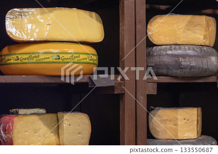 Cheese wheels on wooden shelves in a rustic display with varied textures and colors 133550687