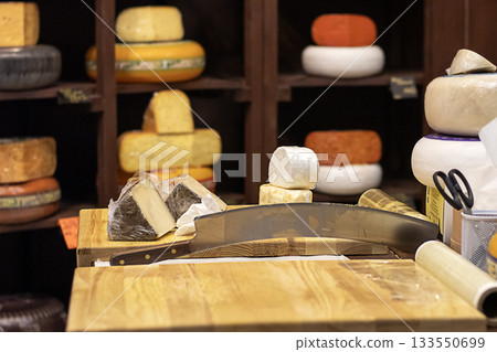 Cheese display with cutting board and cheesewheel in a rustic shop setting for culinary photography Cheese display with cutting board and cheesewheel in a rustic shop setting for culinary photography 133550699