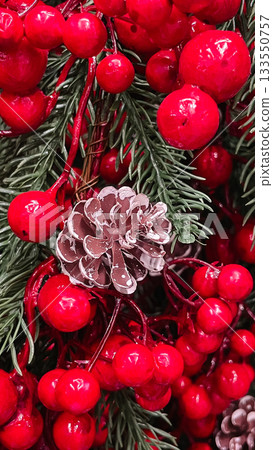 Christmas decor arrangement of red glossy berries frosted pine cone and green pine needles texture background. Christmas decor arrangement of red glossy berries frosted pine cone and green pine needles texture background. 133550757