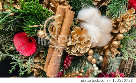Christmas decor arrangement with cinnamon sticks golden pinecones red berries and green pine needles texture Christmas decor arrangement with cinnamon sticks golden pinecones red berries and green pine needles texture 133550758
