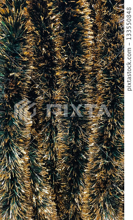 Abstract texture of gold and dark green striped tinsel garland background for Christmas holidays Abstract texture of gold and dark green striped tinsel garland background for Christmas holidays 133550848