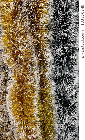 Abstract texture of gold white and black striped festive tinsel garland background for holidays Abstract texture of gold white and black striped festive tinsel garland background for holidays 133550849