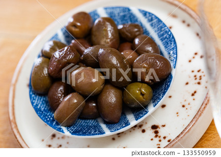 On white plate lies portion of large ripe green olives with stone. 133550959