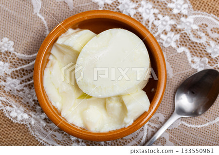 Portion of freshly made homemade cottage cheese is served in earthenware dish. Portion of freshly made homemade cottage cheese is served in earthenware dish. 133550961