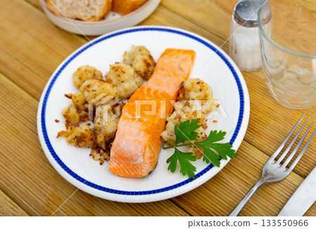 On plate there is piece of fried salmon fillet and vegetable side dish, deep-fried cauliflower On plate there is piece of fried salmon fillet and vegetable side dish, deep-fried cauliflower 133550966