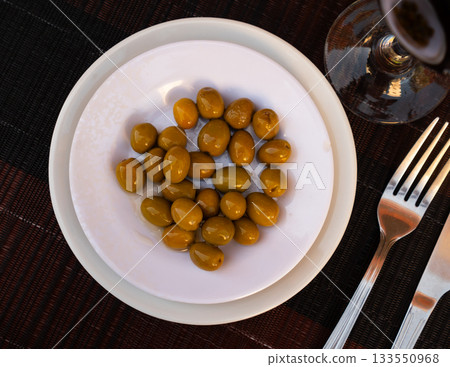 Green olives with pits served in bowl 133550968