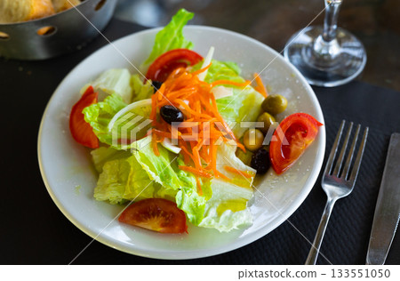 Mixed salad of carrot, lettuce, tomatoes and olives close up 133551050