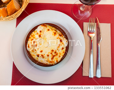 Portion of cannelloni with minced beef, covered with sauce, served on table in restaurant 133551062