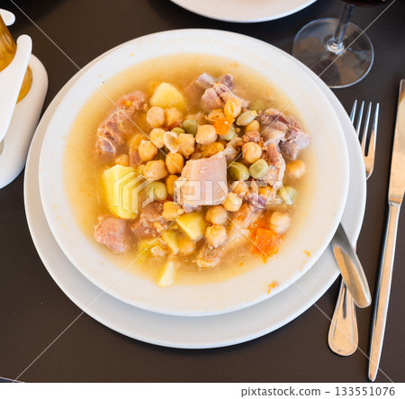 Popular dish of Spanish cuisine is Cocido de garbanzos, made from meat, vegetables and chickpeas, closeup 133551076