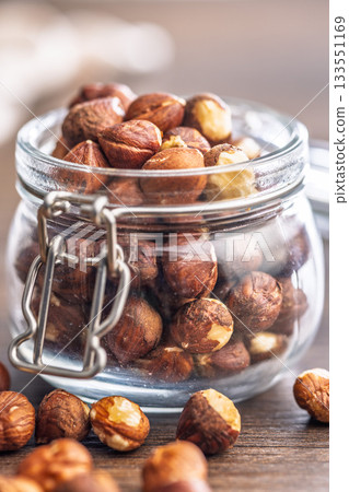 Peeled hazelnut kernels in jar on wooden table. Peeled hazelnut kernels in jar on wooden table. 133551169