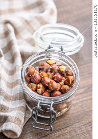 Peeled hazelnut kernels in jar on wooden table. Peeled hazelnut kernels in jar on wooden table. 133551170