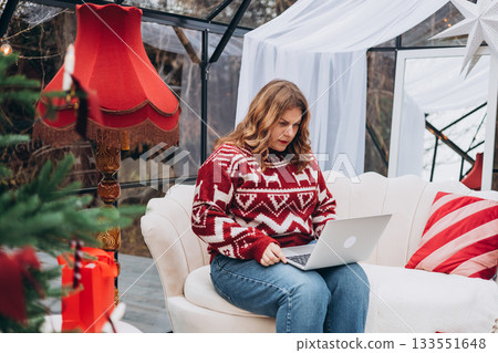 Stressed angry young woman working on laptop, entering wrong payment information, purchasing New year gifts, sitting on the sofa near decorated Christmas tree. Stressed angry young woman working on laptop, entering wrong payment information, purchasing New year gifts, sitting on the sofa near decorated Christmas tree. 133551648