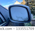 Frost-covered frozen side mirror of a dark-colored car 133551709