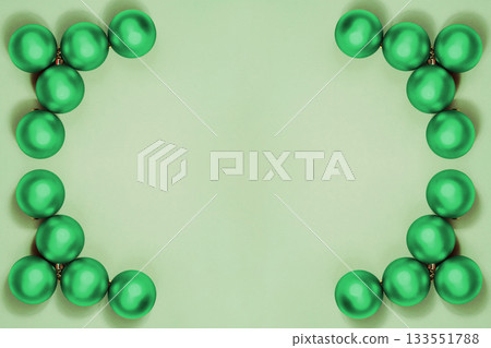 Minimalistic Christmas symmetrical frame composition with monochrome green balls and ribbon on pastel background, ideal for holiday design and festive decoration. New Year, Xmas card with toys Minimalistic Christmas symmetrical frame composition with monochrome green balls and ribbon on pastel background, ideal for holiday design and festive decoration. New Year, Xmas card with toys 133551788