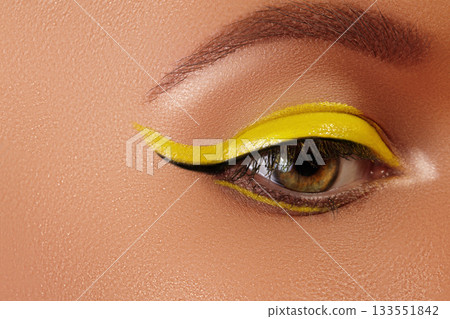 Close-up Female Eye with bright yellow Eyeliner Makeup. Neon Disco make-up and Fashion Manicure. Summer beauty style Close-up Female Eye with bright yellow Eyeliner Makeup. Neon Disco make-up and Fashion Manicure. Summer beauty style 133551842