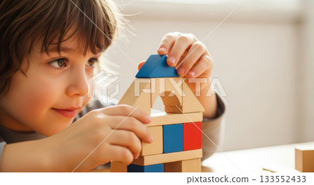 Young boy playing with wooden toy blocks, building a small house. Early childhood development and creativity. 133552433