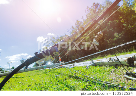 Power lines are down on grass near road following tornado storm, with fallen debris scattered 133552524