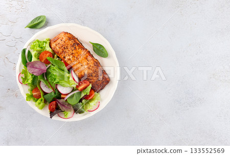 Grilled salmon fillet with fresh leafy greens, cherry tomatoes, radish on white background. Top view Grilled salmon fillet with fresh leafy greens, cherry tomatoes, radish on white background. Top view 133552569