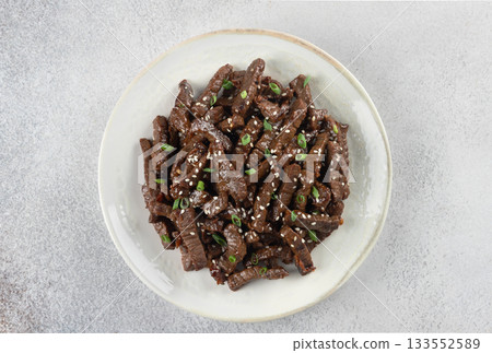 Stir-fried teriyaki beef with sesame seeds on a gray background. Top view. Asian cuisine. Stir-fried teriyaki beef with sesame seeds on a gray background. Top view. Asian cuisine. 133552589