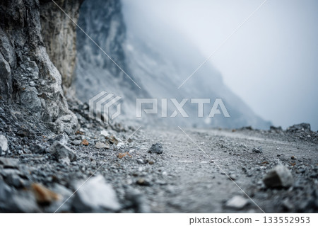 Defocused rocky mountain slope with scattered stones and dust, misty atmosphere, rugged terrain, natural disaster risk, cold gray color, outdoor landscape 133552953