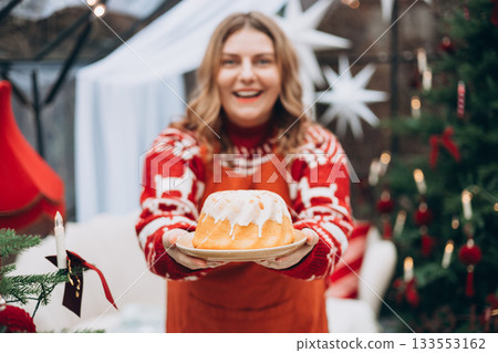 Lemon, vanilla marble bund cake in woman hands. Happy 30s girl standing near decorated Christmas tree. Winter time and holidays. Celebration banner, 133553162