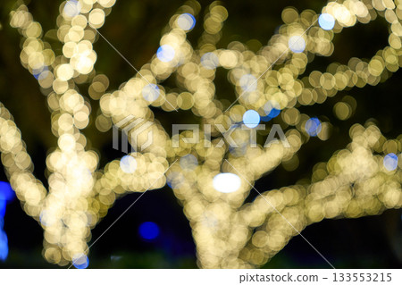 Defocused warm lights form soft round circles in an abstract scene. The dreamy background suggests festive winter illumination. 133553215