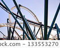 Interlacing loops and supports form an abstract network of steel. The modern roller coaster design stands out against a clear blue sky. 133553270