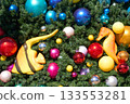 Christmas tree branches are filled with colorful baubles, a yellow tropical fish, and an orange seahorse. Bright holiday ornaments create a playful underwater holiday theme. 133553281