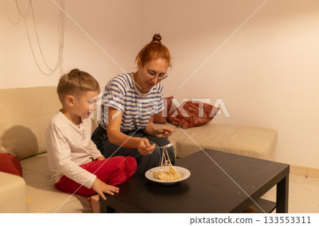 Mother and son enjoying pasta dinner at home 133553311