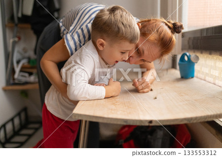 Little boy and mother exploring insect on table 133553312