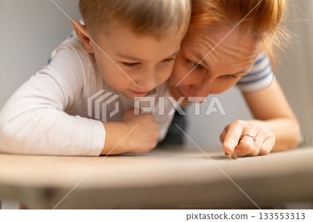 Mother and son exploring table surface with finger Mother and son exploring table surface with finger 133553313