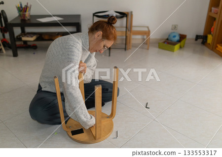 Woman assembling flat pack wooden stool at home Woman assembling flat pack wooden stool at home 133553317