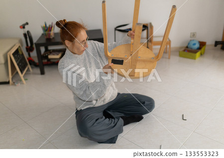 Woman assembling wooden furniture stool at home Woman assembling wooden furniture stool at home 133553323