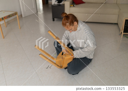 Woman assembling new furniture chair at home 133553325