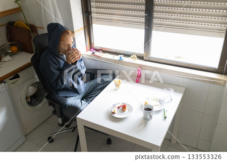 Person relaxing wearing hoodie drinking tea breakfast 133553326