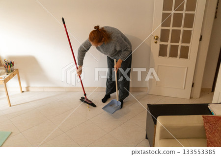 Woman sweeping floor cleaning home with broom 133553385