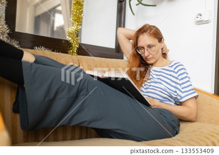 Woman relaxing at home, enjoying reading book Woman relaxing at home, enjoying reading book 133553409