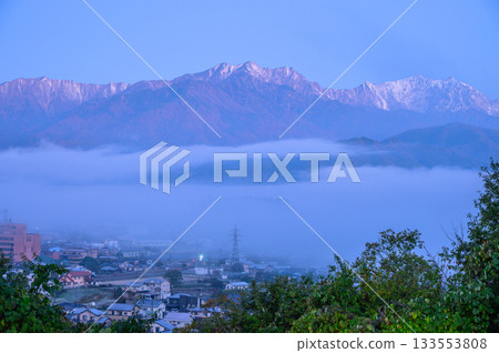 Omachi cityscape shrouded in morning mist and the Tateyama mountain range at dawn Omachi cityscape shrouded in morning mist and the Tateyama mountain range at dawn 133553808