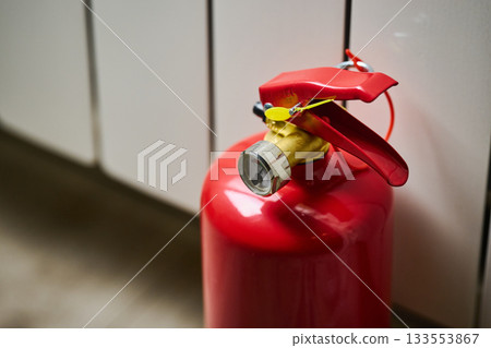 A red fire extinguisher is resting on the floor. 133553867